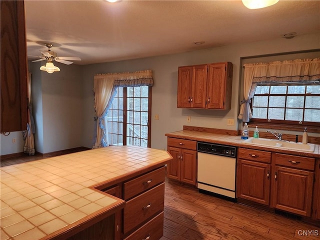 kitchen with light wood-type flooring, white dishwasher, ceiling fan, sink, and tile countertops