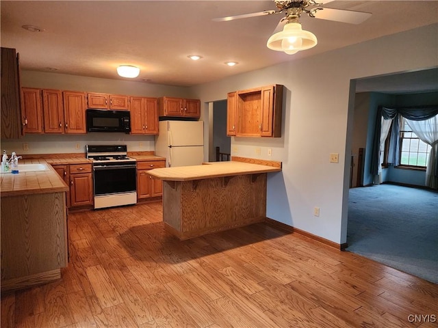 kitchen featuring sink, white appliances, kitchen peninsula, and light wood-type flooring