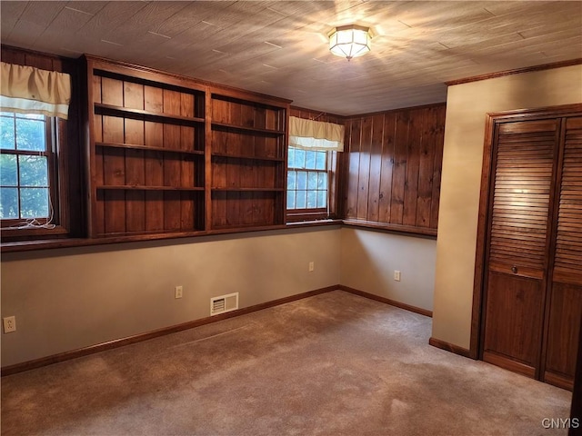 spare room with wooden ceiling, light colored carpet, and wooden walls