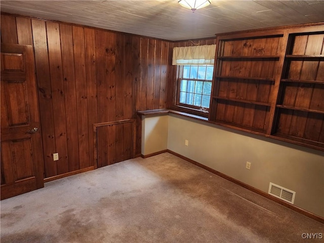 carpeted empty room featuring wood walls