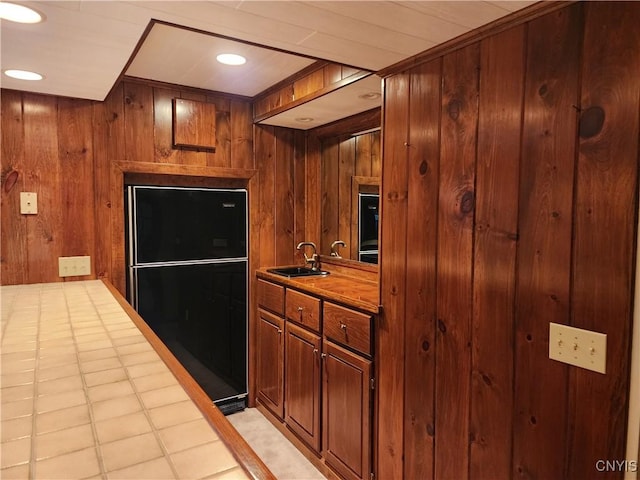 kitchen with sink, refrigerator, and wood walls