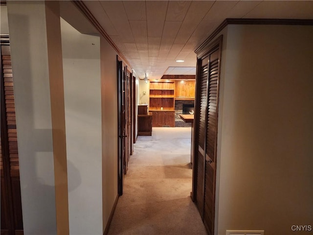 hallway featuring light carpet, crown molding, and baseboards