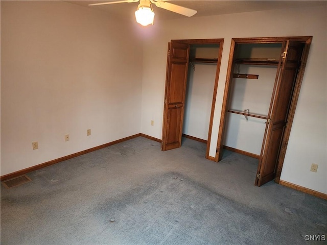 unfurnished bedroom featuring baseboards, carpet, a ceiling fan, and multiple closets