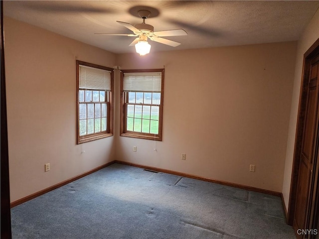 carpeted empty room with a textured ceiling, baseboards, and a ceiling fan