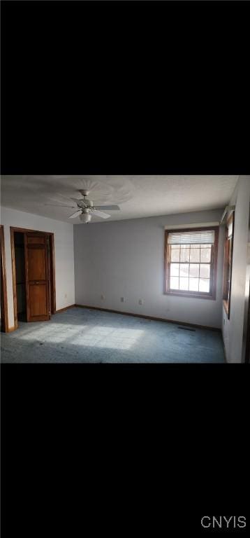 carpeted spare room featuring a ceiling fan