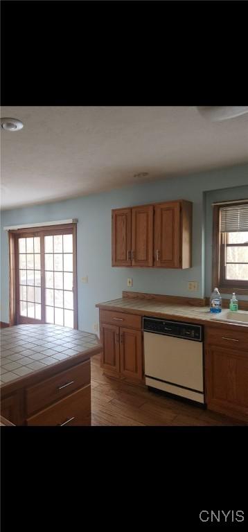 kitchen with white dishwasher, tile countertops, and light wood finished floors