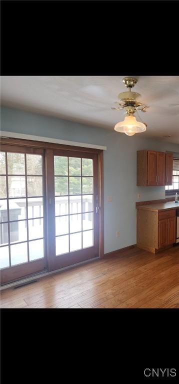 kitchen with light countertops, stainless steel dishwasher, light wood-type flooring, and brown cabinets