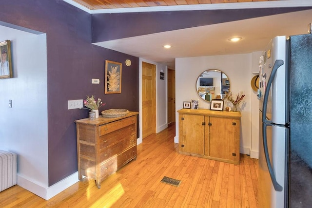 kitchen featuring radiator, light wood-style floors, baseboards, and freestanding refrigerator