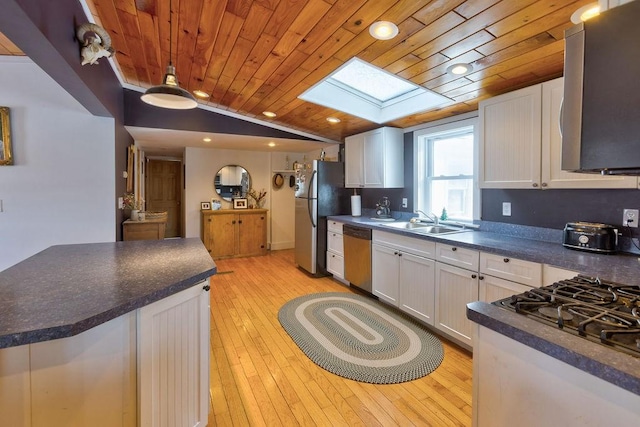 kitchen featuring appliances with stainless steel finishes, dark countertops, white cabinets, and a sink