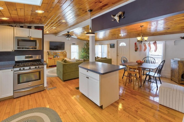 kitchen with open floor plan, stainless steel appliances, hanging light fixtures, and dark countertops