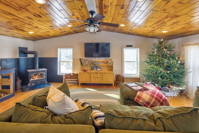 living area with lofted ceiling, a ceiling fan, a wood stove, light wood-type flooring, and wooden ceiling