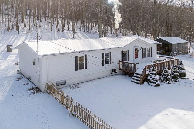 snow covered property with a wooden deck and an outdoor structure