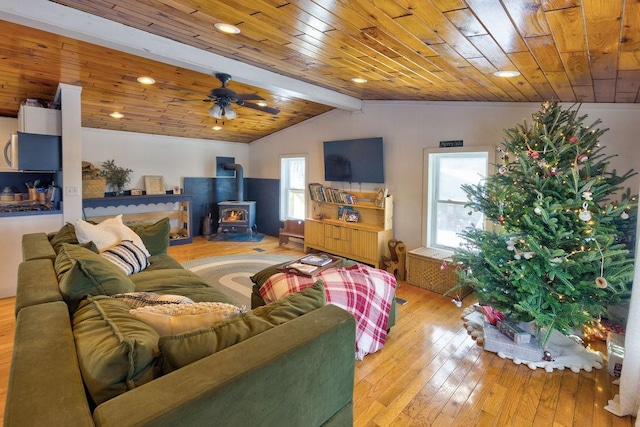 living room with light wood-type flooring, a wood stove, wooden ceiling, and vaulted ceiling with beams