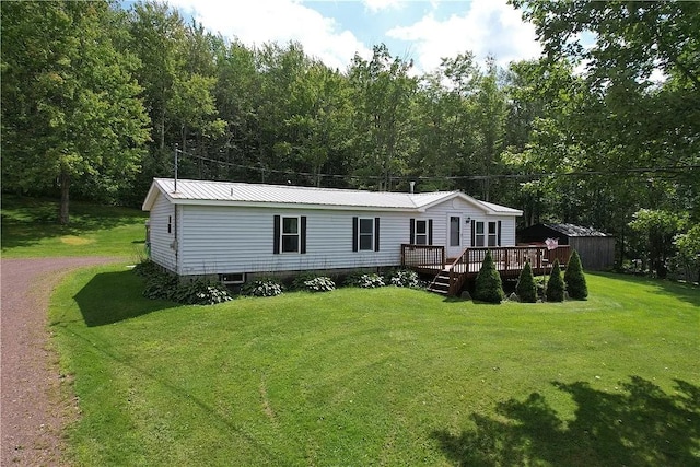 view of front facade featuring a storage unit, a front yard, metal roof, a deck, and driveway