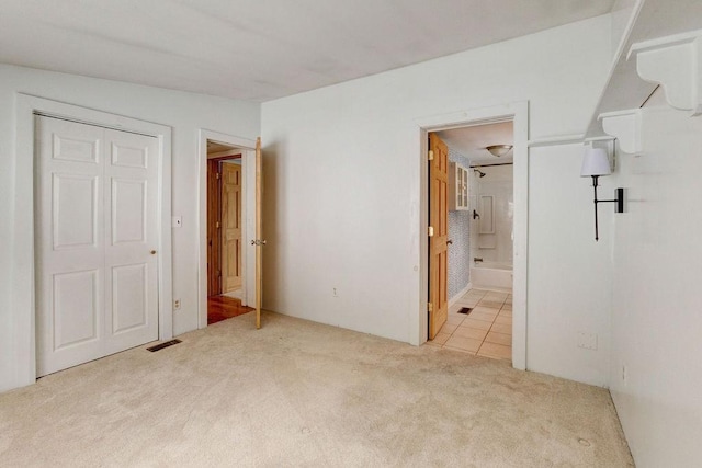 unfurnished bedroom featuring light carpet and ensuite bath