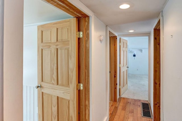 hall featuring light wood finished floors and visible vents