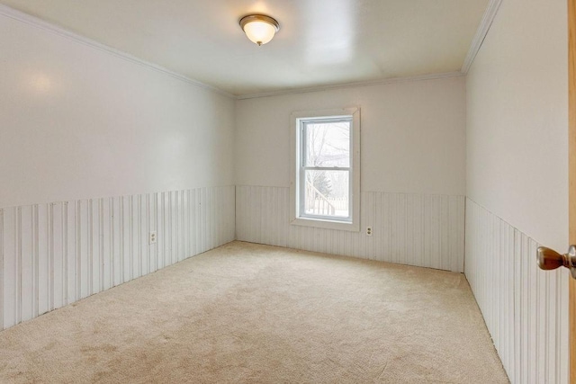 unfurnished room with wainscoting, crown molding, and light carpet