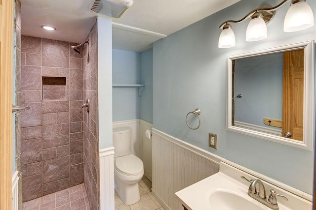 bathroom featuring toilet, a wainscoted wall, vanity, a shower stall, and tile patterned floors