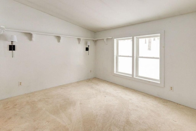 spare room with light carpet and lofted ceiling