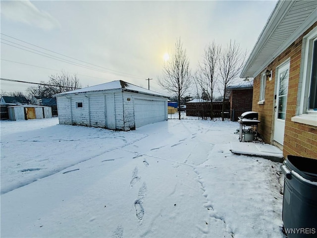 yard covered in snow featuring a garage and a shed