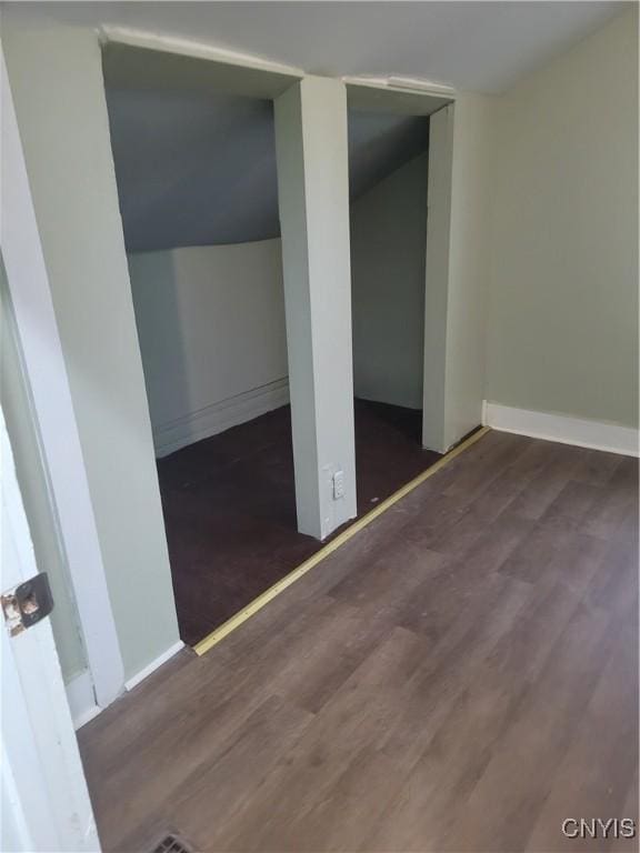 unfurnished bedroom featuring lofted ceiling and dark wood-type flooring