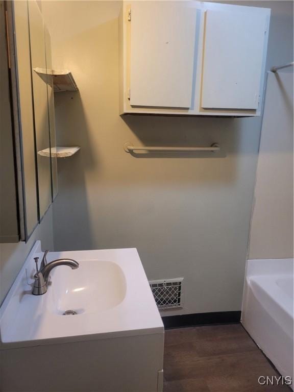 bathroom featuring a tub to relax in, sink, and wood-type flooring