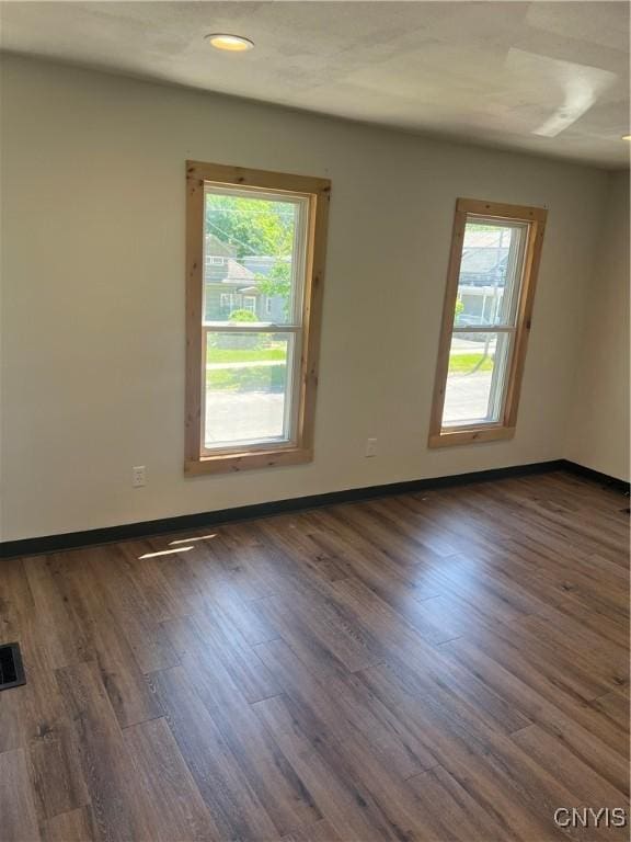 unfurnished room featuring dark hardwood / wood-style flooring and a healthy amount of sunlight