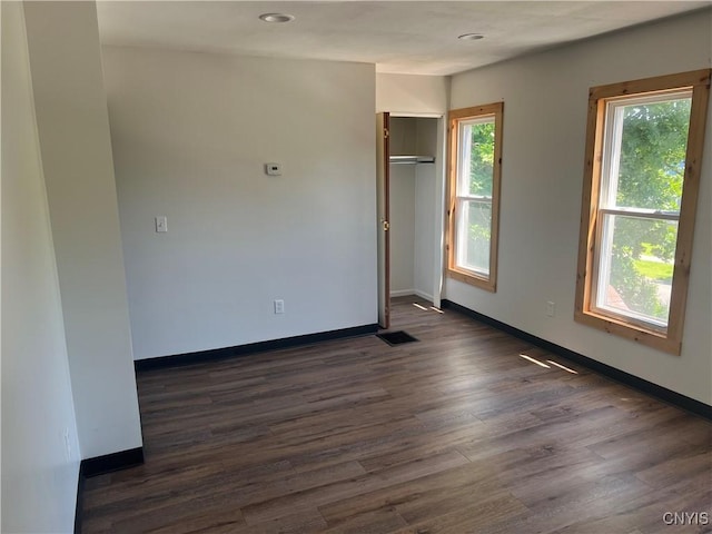 spare room with plenty of natural light and dark wood-type flooring