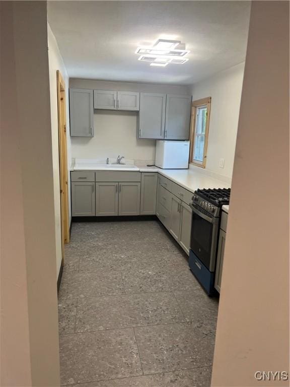 kitchen featuring gray cabinetry, black gas stove, and sink