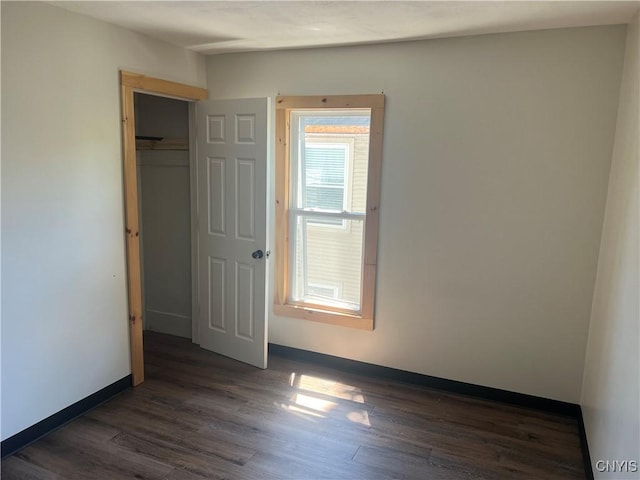 unfurnished bedroom with a closet and dark hardwood / wood-style floors