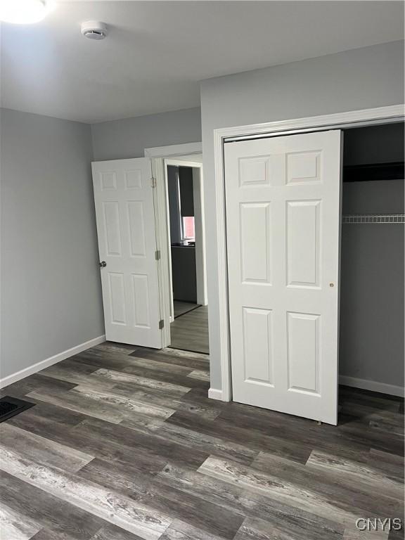 unfurnished bedroom with dark hardwood / wood-style flooring and a closet