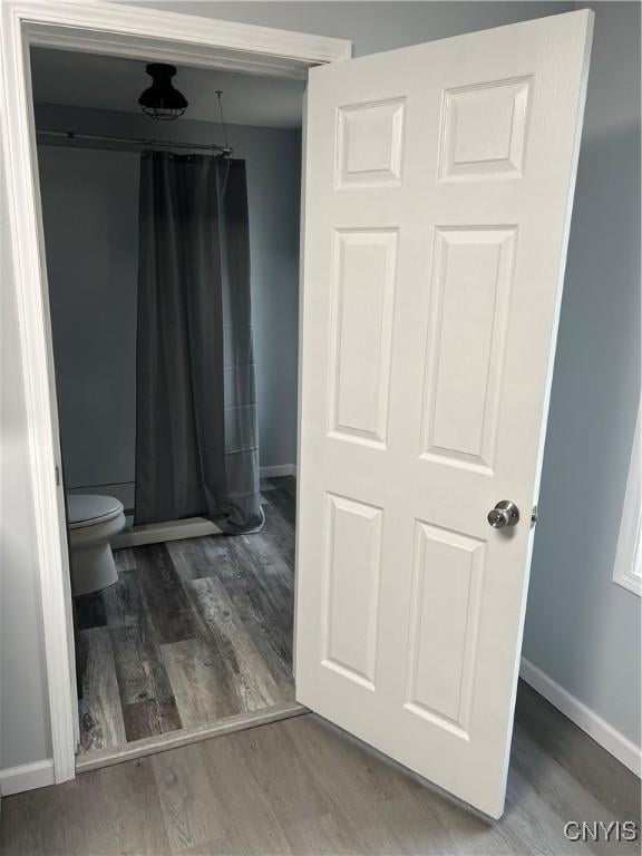 bathroom featuring a shower with shower curtain, wood-type flooring, and toilet