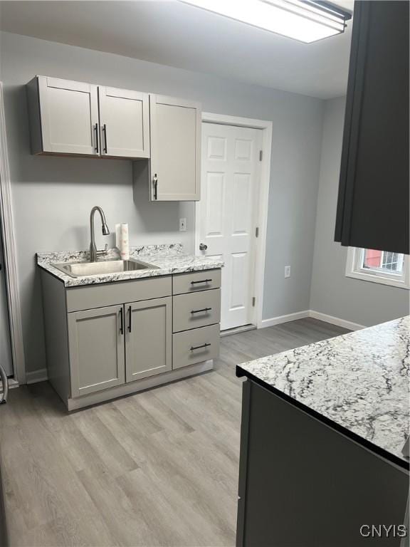 kitchen featuring gray cabinetry, white cabinets, light wood-type flooring, and sink