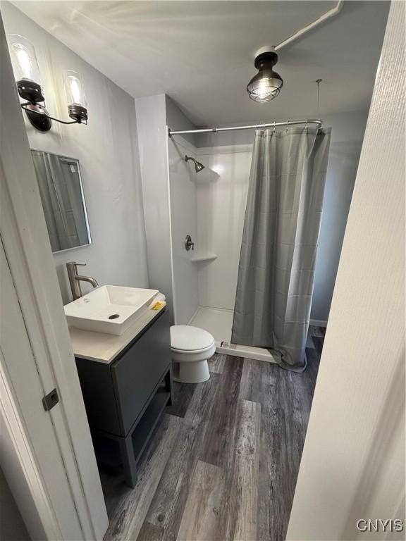 bathroom featuring hardwood / wood-style floors, vanity, toilet, and curtained shower