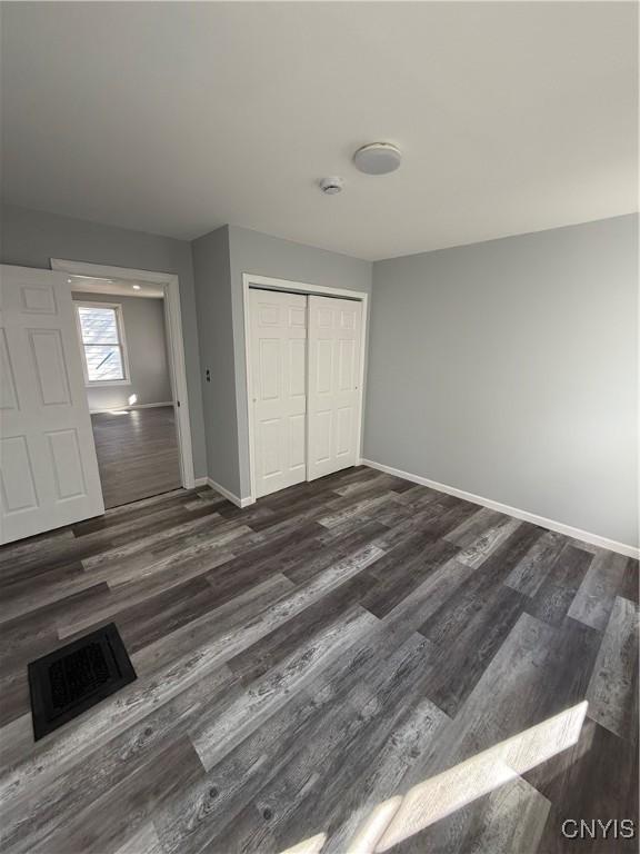 unfurnished bedroom featuring a closet and dark wood-type flooring