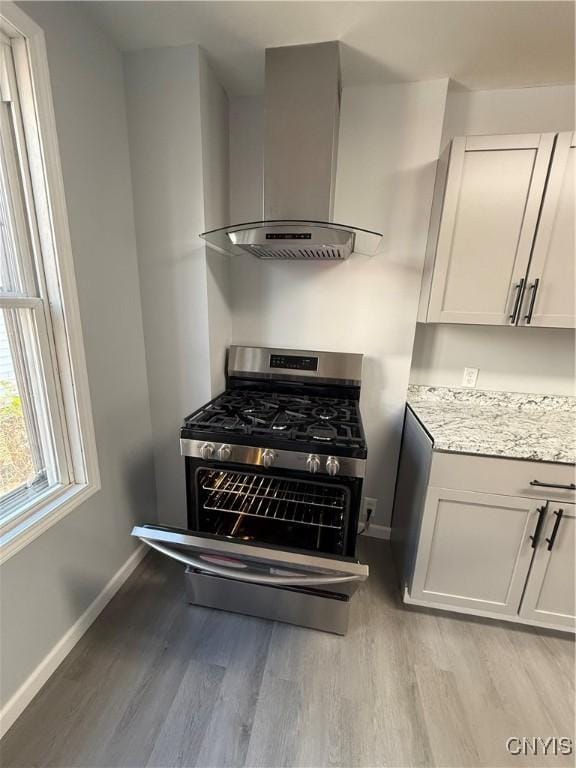 kitchen featuring white cabinetry, stainless steel range with gas cooktop, and wall chimney exhaust hood