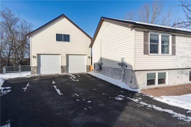 view of snow covered exterior featuring ac unit and a garage