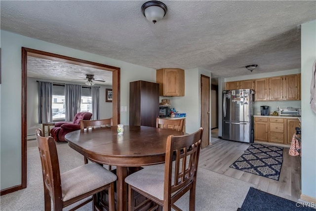 dining area featuring baseboard heating, ceiling fan, light hardwood / wood-style flooring, and a textured ceiling