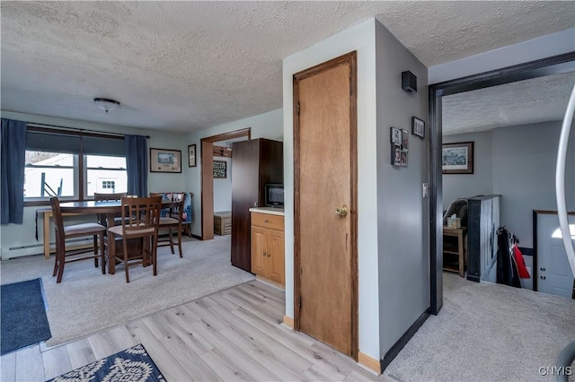 kitchen with a textured ceiling, light wood-type flooring, and a baseboard heating unit