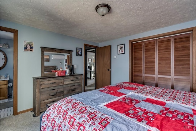 carpeted bedroom featuring a textured ceiling, ensuite bathroom, a closet, and a wall mounted air conditioner