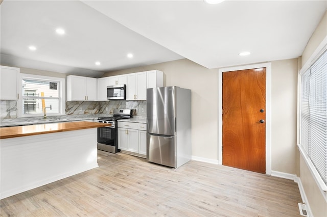 kitchen with sink, stainless steel appliances, light hardwood / wood-style flooring, backsplash, and white cabinets