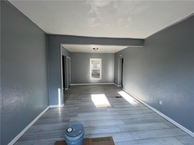 unfurnished room with beamed ceiling and wood-type flooring