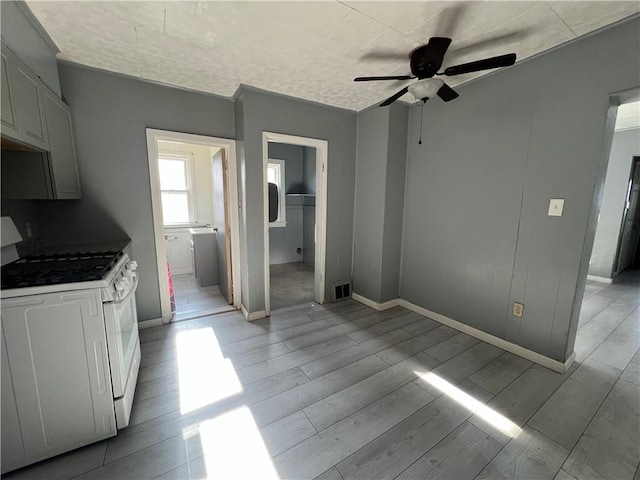 kitchen featuring white gas range oven, white cabinetry, and ceiling fan