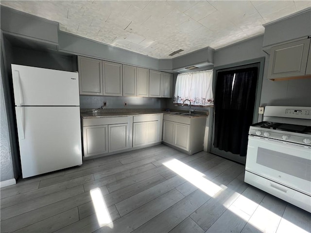 kitchen featuring sink, light hardwood / wood-style floors, and white appliances