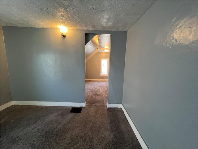 carpeted spare room featuring lofted ceiling and a textured ceiling