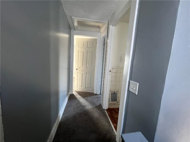 corridor with a textured ceiling and dark colored carpet