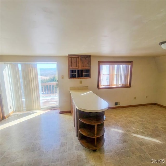 kitchen featuring a wealth of natural light, light countertops, baseboards, and open shelves