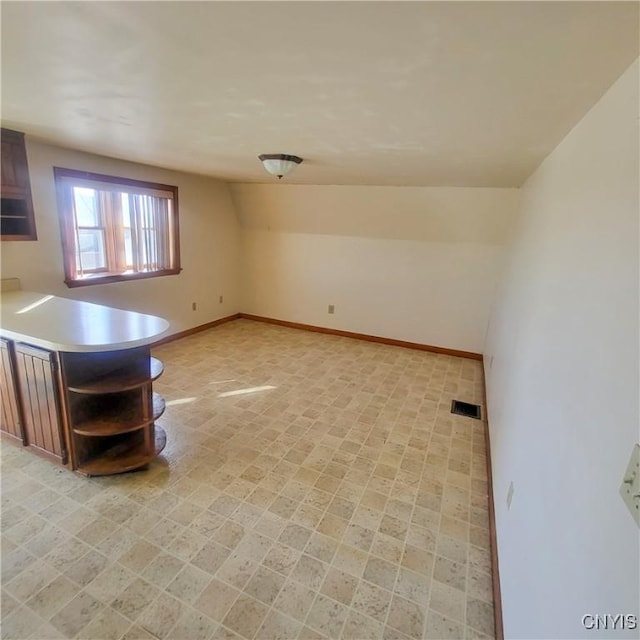 kitchen with lofted ceiling, visible vents, baseboards, light countertops, and open shelves