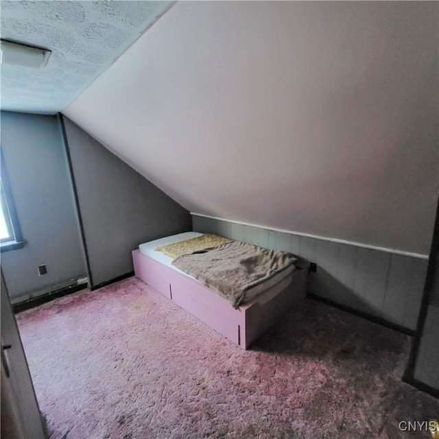 carpeted bedroom featuring vaulted ceiling and a textured ceiling