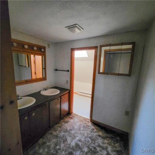 bathroom with a sink, a textured ceiling, and double vanity